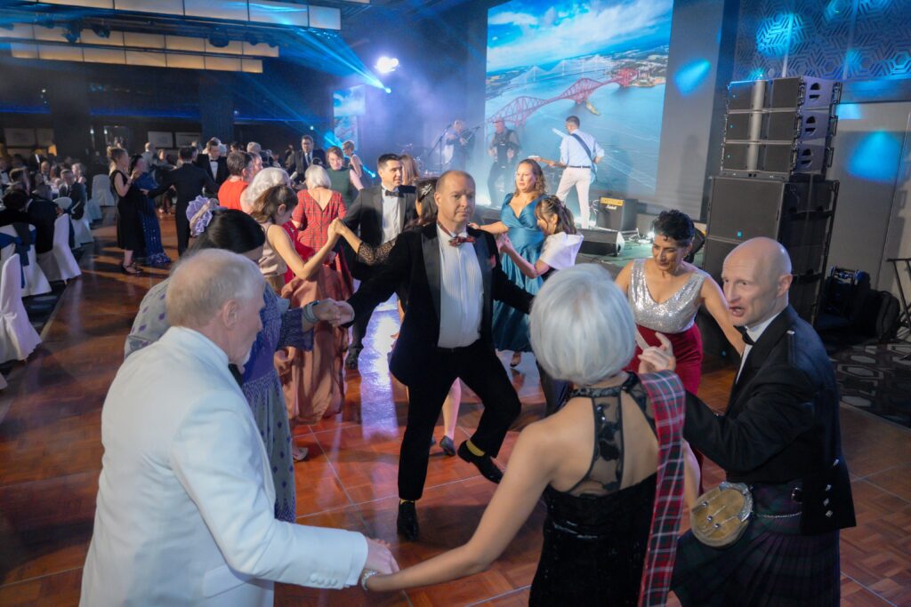 Men and women in evening dress dancing to ceilidh music